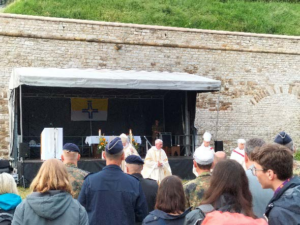 Auf dem Foto blickt man über einige Köpfe hinweg auf eine Bühne, auf der ein Altar aufgebaut ist.